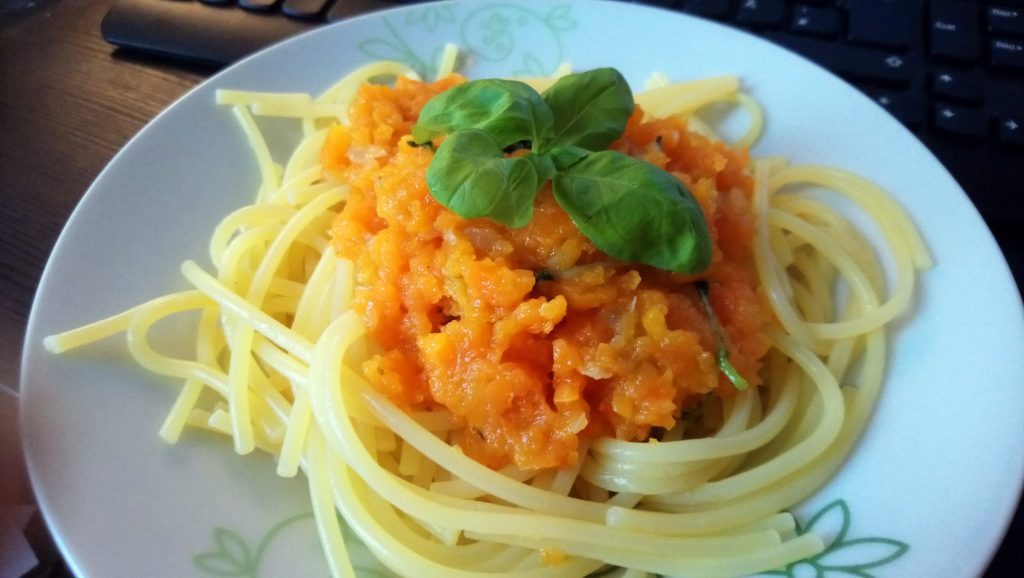 Auf einem Teller sind Spaghetti mit einer Möhrensoße platziert. Dekoriert wird das Gericht mit einem Basilikumzweig. Wenn man auf das Bild klickt gelangt man zum eiweißarmen Rezept für Menschen mit PKU.