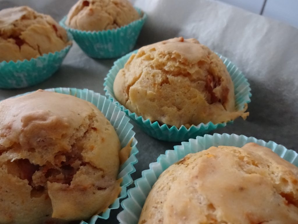 Man sieht ein Backblech mit fünf Muffins. Es sind herzhafte Muffins und sie stecken in türkisen Muffinförmchen. Wenn man auf das Bild klickt gelangt man zum eiweißarmen Rezept für Menschen mit PKU.
