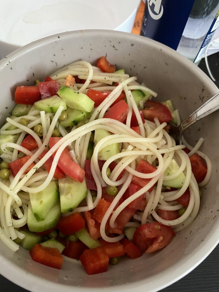 Nudelsalat aus eiweißarmen Spaghetti, Gurke, Paprika, Erbsen und Dressing in einer grauen Schüssel